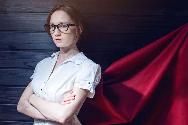 Superwoman trabajadora de oficina de pie en un traje y capa roja
 - Foto, Imagen