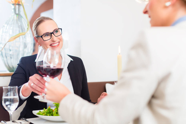 Frauen stoßen beim Business Lunch mit Wein an - Foto, Bild