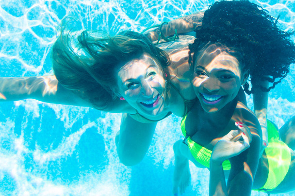 Vrienden onderwater duiken in zwembad - Foto, afbeelding