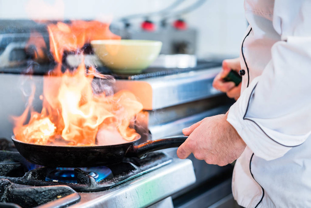 Chef haciendo flambe para plato en sartén
 - Foto, imagen