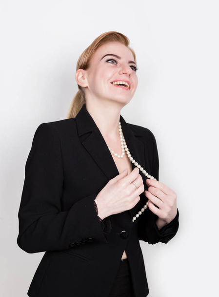 Attractive and energetic business woma in a suit on naked body smiling, holding pearls - Photo, Image