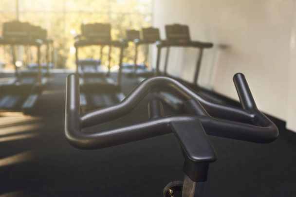 Modern gym interior with equipment, fitness exercise bike handlebar - 写真・画像