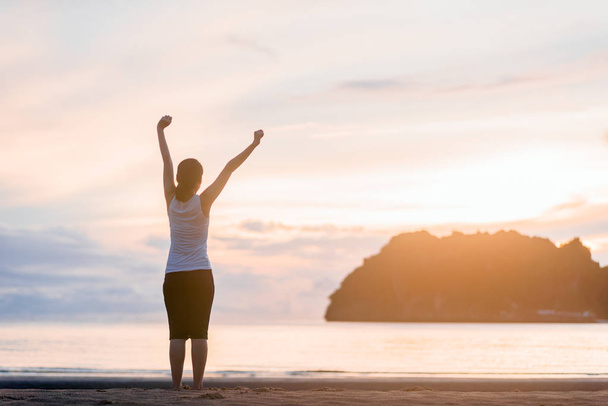 Расслабленная женщина дышит свежим воздухом на пляже на восходе солнца
. - Фото, изображение