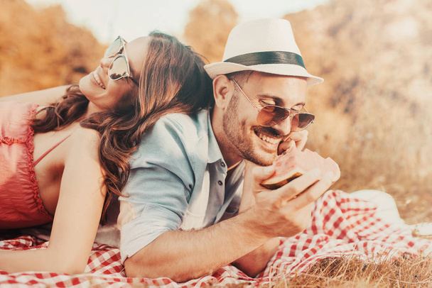 Feliz pareja joven disfrutando de un picnic en el parque
 - Foto, Imagen