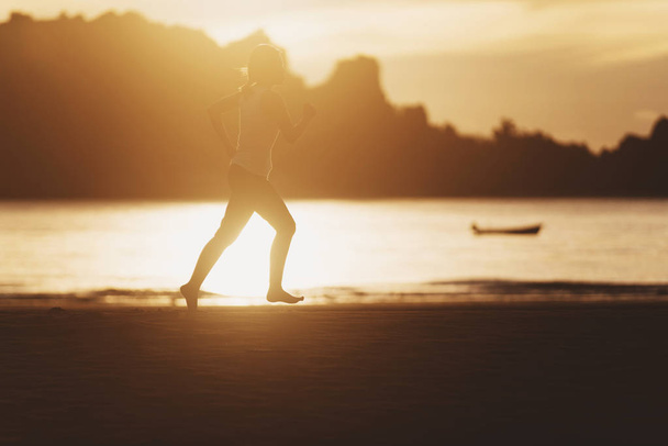 Instagram, κοιτάζοντας την εικόνα της γυναίκας που τρέχει στην παραλία με την Ανατολή. - Φωτογραφία, εικόνα