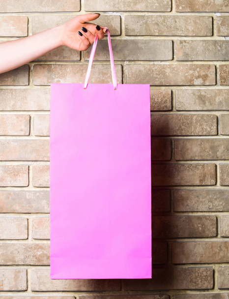 pink shopping bag in female hand on brick wall - Фото, зображення