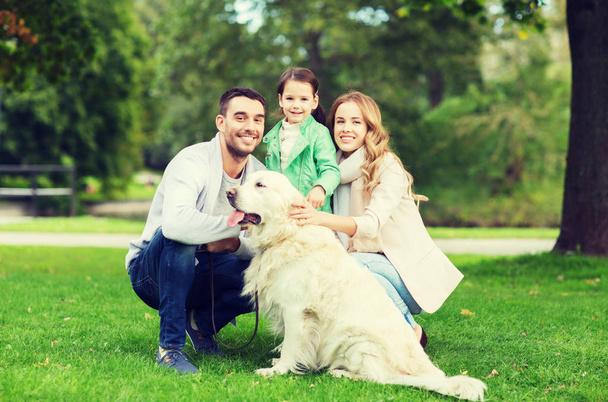 happy family with labrador retriever dog in park - Foto, afbeelding