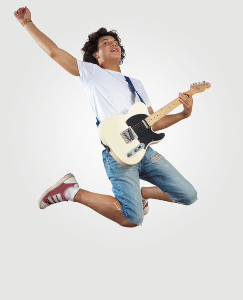 Young man playing on electro guitar and jumping - Foto, Imagen