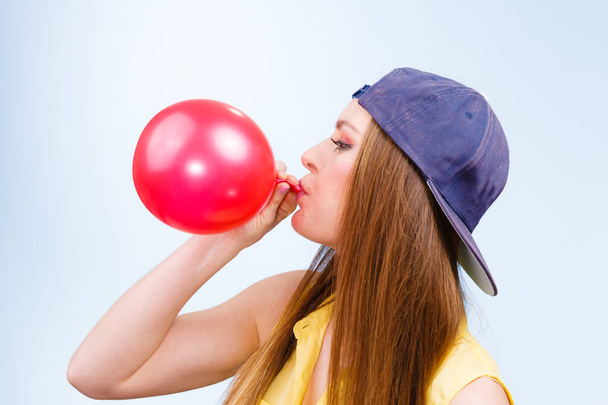 Kobiece kobieta młody nastolatek pompowania czerwony balon. - Zdjęcie, obraz