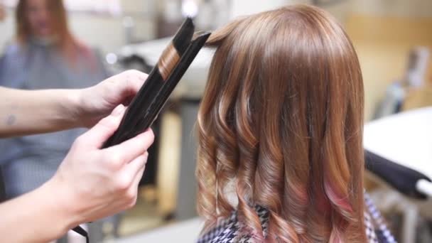 Fryzjer sprawia, że kręcone włosy kobieta przez gorąco curling, Kobieta w branży beauty studio, mody i urody - Materiał filmowy, wideo