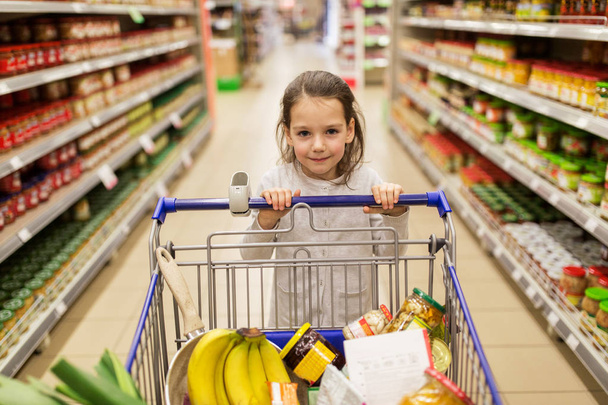 girl with food in shopping cart at grocery store - Photo, Image