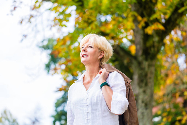 Senior woman having walk in autumn park - Фото, зображення