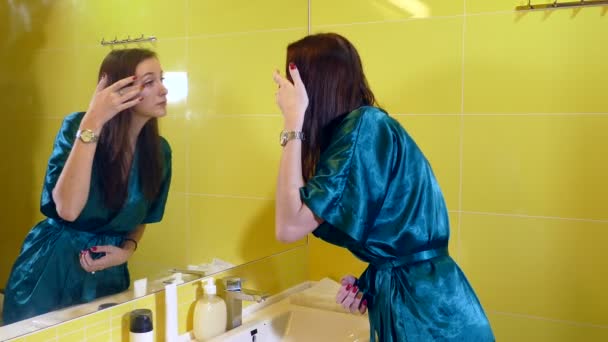 Young woman looking at the mirror in the bathroom - Materiał filmowy, wideo