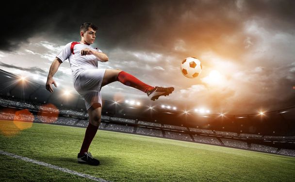 Футболист пинает мяч на стадионе
. - Фото, изображение