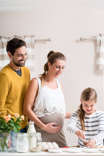 Famiglia con madre incinta che cucina insieme in cucina
 - Foto, immagini