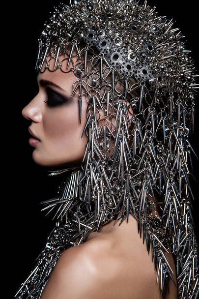 High fashion beauty model with metallic headwear and dark makeup and blue eyes on black background - Foto, Imagem
