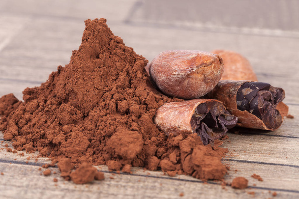 Какао-бобы и порошок на деревянной доске
 - Фото, изображение