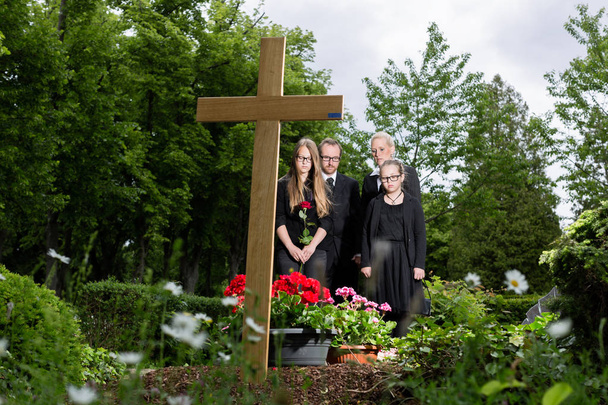 Perhe suree haudalla hautausmaalla
 - Valokuva, kuva