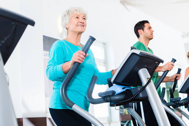 Femme âgée sur un entraîneur elliptique faisant de l'exercice dans une salle de gym
 - Photo, image