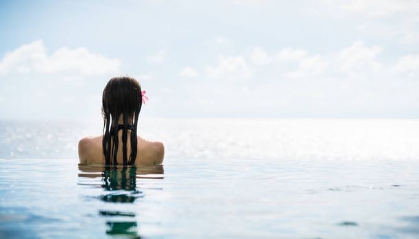 Жінка-туристка в нескінченному басейні готельного курорту в океані
 - Фото, зображення