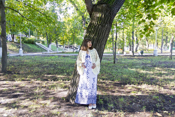 Pregnant woman with brown hair in park - Zdjęcie, obraz