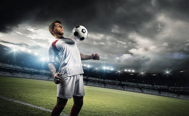 Football player withstand a ball with his chest in the stadium - Foto, imagen