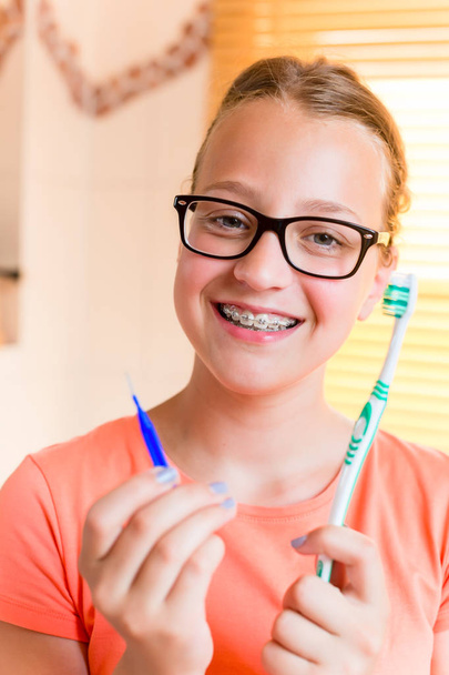 Chica adolescente con frenos dentales cepillándose los dientes
 - Foto, imagen