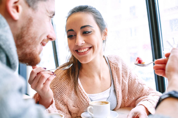couple eating a dessert spoon in cafe on date - Foto, afbeelding