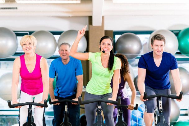 Grupo de hombres y mujeres girando en bicicletas de fitness en el gimnasio
 - Foto, imagen
