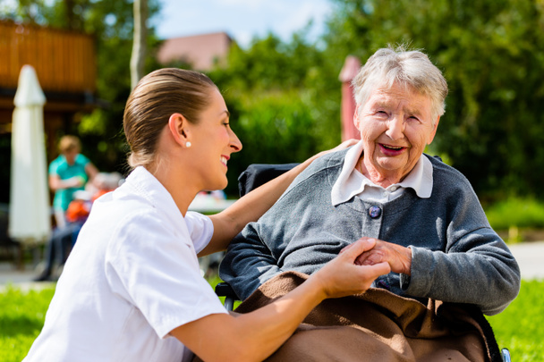 Zdravotní sestra držel ruku s starší žena na vozíku - Fotografie, Obrázek