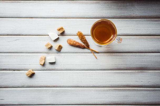 Una taza de té y azúcar de caña. Sobre fondo de madera
. - Foto, imagen
