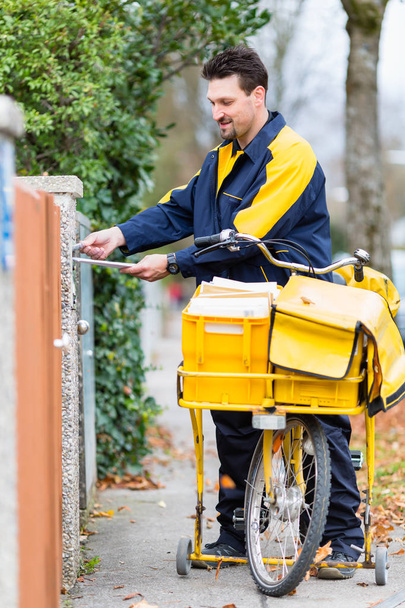 Postman delivering letters to mailbox - Foto, afbeelding