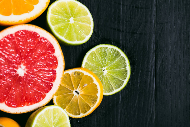 Świeżych owoców cytrusowych stihli. Cytryny, limonki, grejpfruta i pomarańczy na czarnym tle - Zdjęcie, obraz