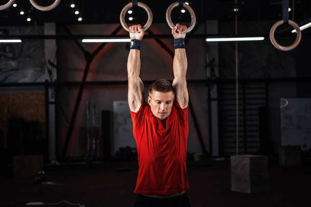 Atleta exercitando seus músculos em anéis
 - Foto, Imagem