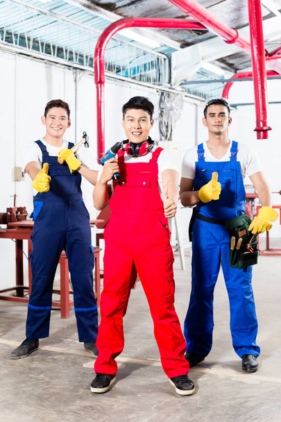 Três trabalhadores industriais asiáticos orgulhosos na fábrica
 - Foto, Imagem