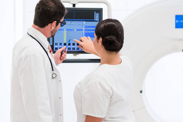 Médico e enfermeiro analisando dados da tomografia computadorizada
 - Foto, Imagem