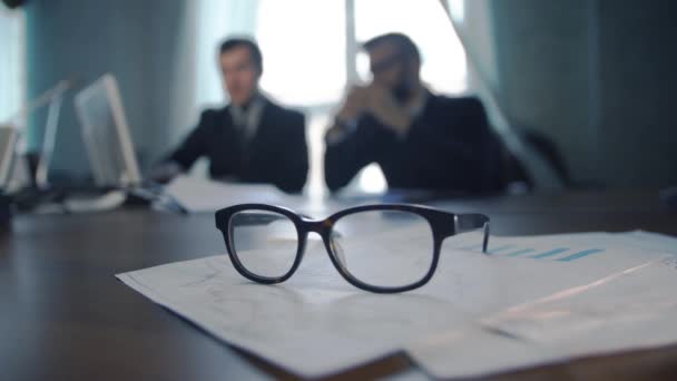 financial chart near dollars seen by unfocused glasses ( colleagues meeting to discuss their future financial plans only silhouettes being viewed ) - Footage, Video