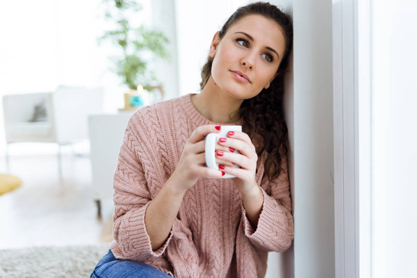 mooie jonge vrouw drinken koffie thuis. - Foto, afbeelding