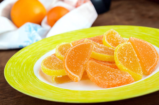 柑橘類のスライスの形でお祝いお菓子カラフルなゼリー菓子は暗い背景の木に砂糖で覆われています。クローズ アップ - 写真・画像
