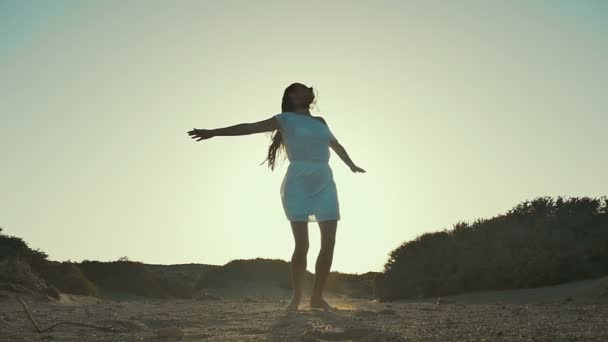 Meisje in witte jurk meisje wervelende bij zonsondergang achtergrond. Woestijn. Slow motion. - Video