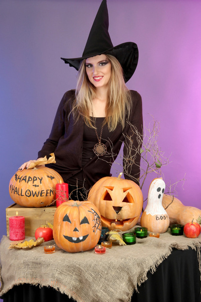 Halloween witch with pumpkins on color background - Foto, afbeelding