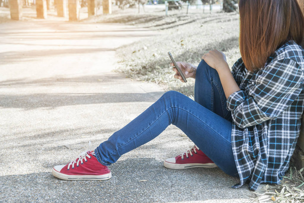 magányos lány ül a parkban, használ neki telefont - Fotó, kép