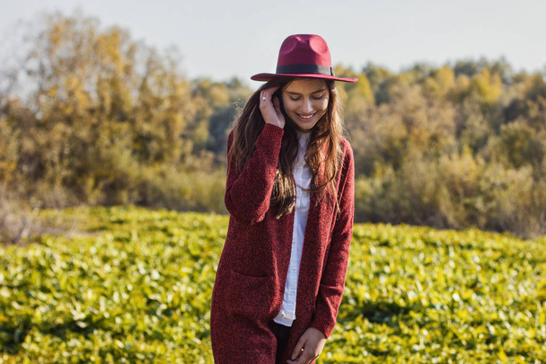 Милая девушка в красном кардигане и шляпе осенью
 - Фото, изображение