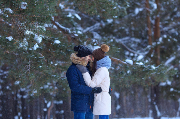 Счастливая пара обнимается зимой в снежных лесах
 - Фото, изображение