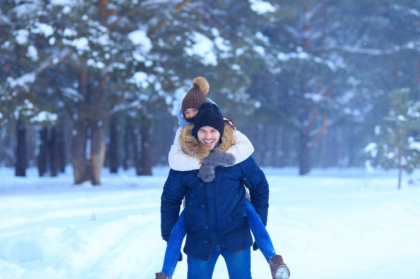 雪に覆われた森の中で野外を歩いている遊び心のあるカップル - 写真・画像