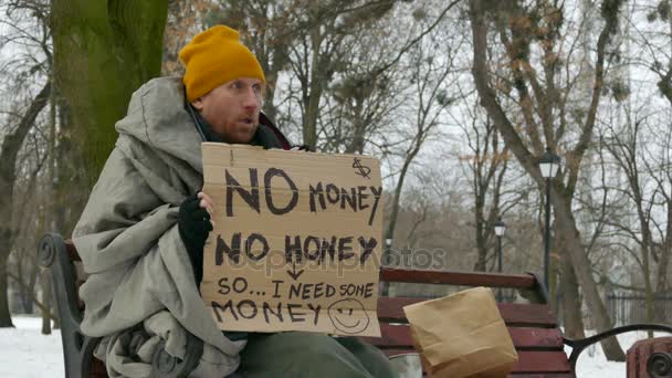   段ボールで 4 k. アダルト ホームレスの貧しい男冬市のベンチに座っているし、咳 - 映像、動画