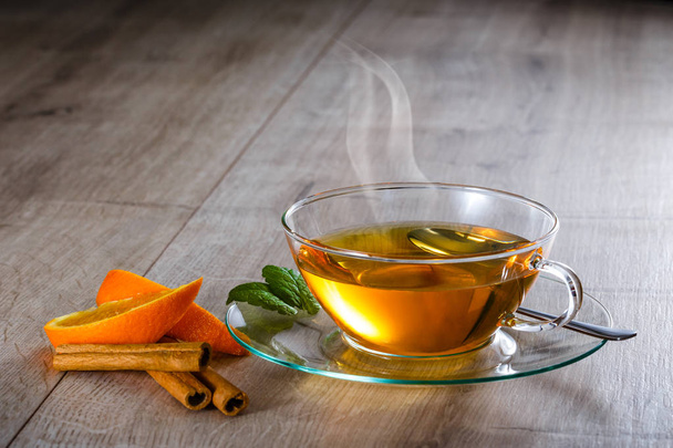 Tè caldo invernale in vetro con bastoncino di arancia e cannella
 - Foto, immagini