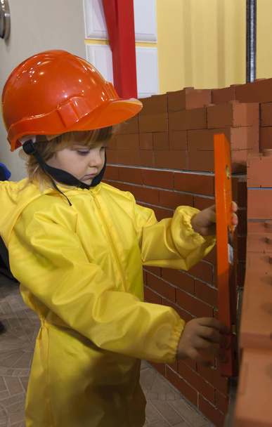 Criança com ferramenta perto da parede de tijolo
 - Foto, Imagem