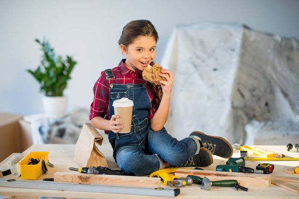 Little girl eating in workshop - Фото, изображение