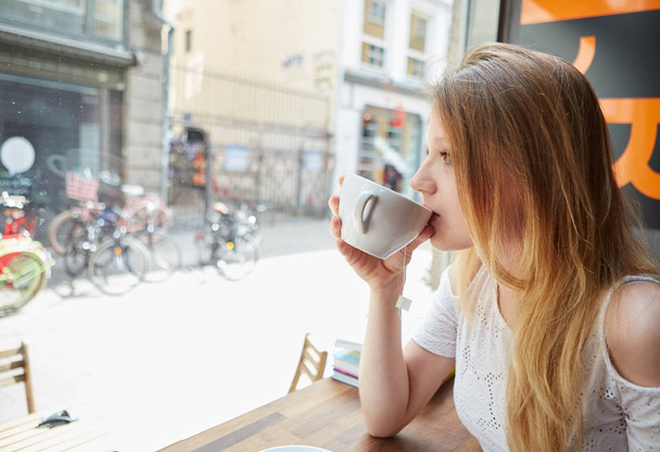 A shot of a beautiful woman drinking coffee in a cafe - Photo, image